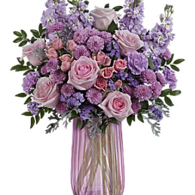 What a delight! Overflowing with pink roses and lavender blooms, this decadent Mother's Day bouquet shines in an iridescent pink glass vase that Mom is sure to adore.
